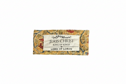 Pair of old eyeglasses with a decorative box labeled 'Jesus Christ King of Kings Lord of Lords' on a gray background.