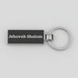 Black keychain with 'Jehovah Shalom' text on a light gray background